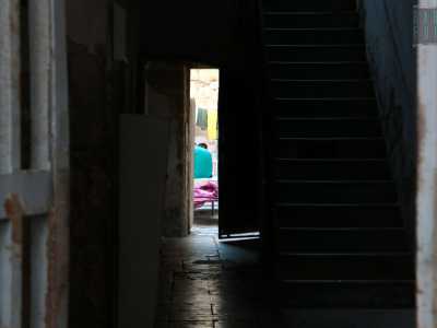 In un androne buio e poco curato intravediamo panni coloratissimi e uomini dalla carnagione scura